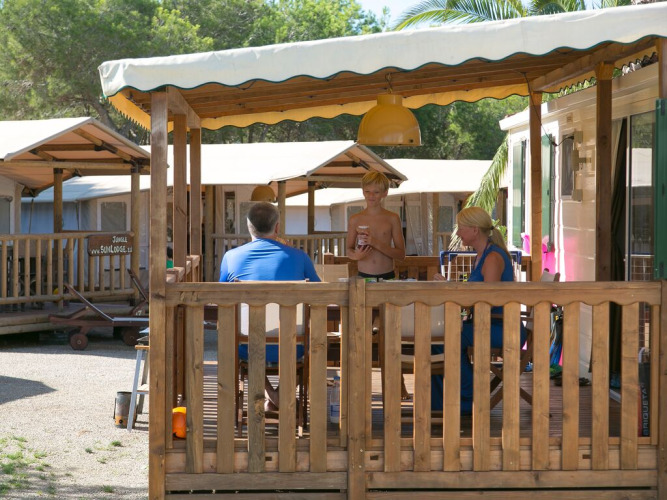 Famille profite de la terrasse d’un chalet SunLodge Maple au Camping Vilanova Park en Espagne.