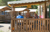 Familia disfruta en la terraza de una cabaña SunLodge Maple en Camping Vilanova Park, España.