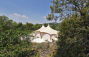 Tienda safari RoyalLodge entre árboles en Slow Village Provence Occitane, bajo cielo azul en Francia.