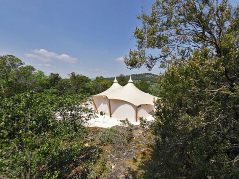 Tienda safari RoyalLodge entre árboles en Slow Village Provence Occitane, bajo cielo azul en Francia.