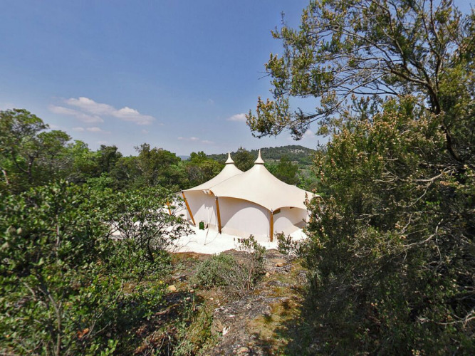 Tienda safari RoyalLodge entre árboles en Slow Village Provence Occitane, bajo cielo azul en Francia.