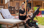 Mother sits on a lounge chair next to a stroller and her baby outside SunLodge BigLeaf in Italy.