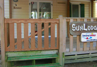 Entrada de SunLodge Redwood en Camping Cisano/San Vito, Italia, con porche de madera y letreros visibles.