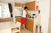 Vrouw maakt thee in de kitchenette van SunLodge Redwood Premium op Camping Cisano/San Vito in Italië.