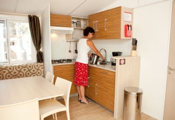 Woman making tea in the kitchenette at SunLodge Redwood Premium, Camping Cisano/San Vito in Italy.