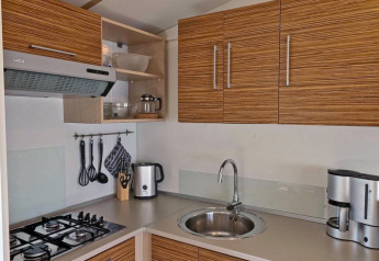 Moderne kitchenette in een lodge met gasfornuis, gootsteen, waterkoker, koffiezetapparaat en houtlook kasten.
