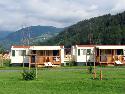 SunLodge Maple chalets bij Camping Bella Austria in Oostenrijk, omgeven door grasvelden en heuvels.