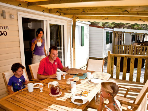 Family enjoys breakfast on the terrace of SunLodge Aspen Combi at Camping Leï Suves in France.