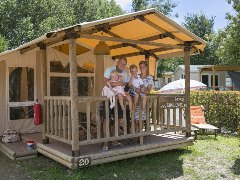 Familia disfruta en el porche de una SunLodge Safari en Camping Pra'delle Torri, Italia.