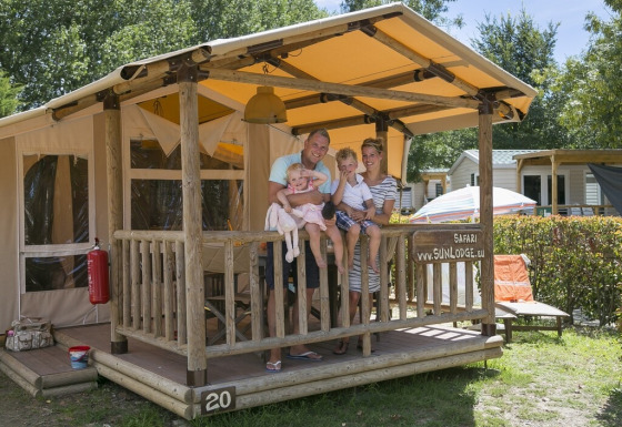 Family enjoying vacation on the porch of a SunLodge Safari at Camping Pra'delle Torri in Italy.