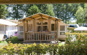 En SunLodge Safari-hytte på Camping Pra'delle Torri i Italien, omgivet af grønne planter og træer.
