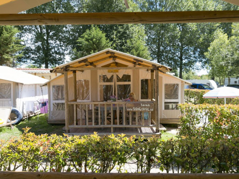 A SunLodge Safari cabin at Camping Pra'delle Torri in Italy, surrounded by greenery and outdoor ambiance.