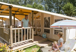 Familia disfrutando al aire libre frente a SunLodge Safari en Camping Pra'delle Torri, Italia, con sol y relax.