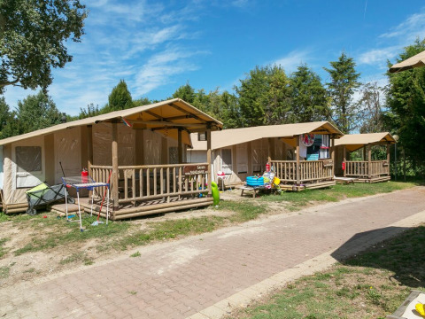 SunLodge Safari tent lodges at Camping Pra'delle Torri, Italy, with porches and trees on a sunny day.