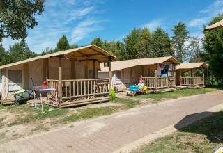 SunLodge Safari tent lodges at Camping Pra'delle Torri, Italy, with porches and trees on a sunny day.