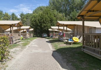 Tiendas SunLodge Safari en Camping Pra'delle Torri, Italia, alineadas en un sendero con vegetación.