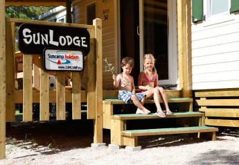 Due bambini seduti sugli scalini della SunLodge Aspen presso hu Park Albatros Village in Italia, al sole.