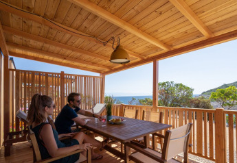 Coppia che si rilassa sulla terrazza in legno della SunLodge BigLeaf al Camping Village Poljana, Croazia, vista mare.