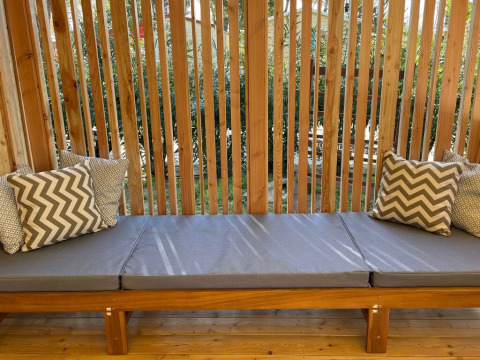 Banco exterior con cojines grises y almohadas en SunLodge Sabai de Camping Gasparina, Italia.