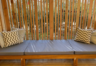 Banco exterior con cojines grises y almohadas en SunLodge Sabai de Camping Gasparina, Italia.