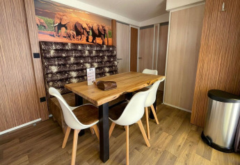 Dining area at SunLodge Sabai, Camping Gasparina, Italy, with wood table, white chairs, and elephant mural.