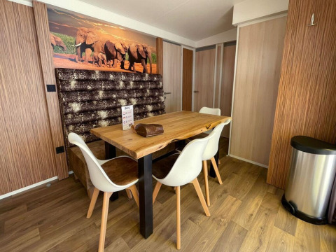 Coin repas à SunLodge Sabai du Camping Gasparina en Italie, avec table en bois et fresque d’éléphants.