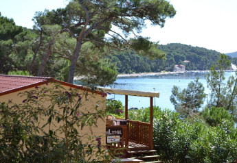 SunLodge Aspen met uitzicht op zee, omringd door bomen en groene heuvels op de achtergrond.