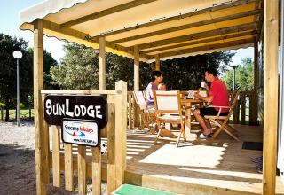 Familia desayunando en la terraza de madera bajo toldo en SunLodge Aspen, Camping Village Poljana, Croacia.