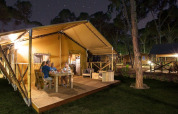 Familia cenando en la terraza de madera de SunLodge Bintulu en Camping Village Poljana, Croacia, de noche.