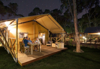Family dining on the wooden terrace of SunLodge Bintulu at Camping Village Poljana in Croatia at night.