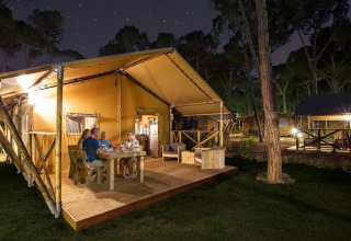 Familia cenando en la terraza de madera de SunLodge Bintulu en Camping Village Poljana, Croacia, de noche.