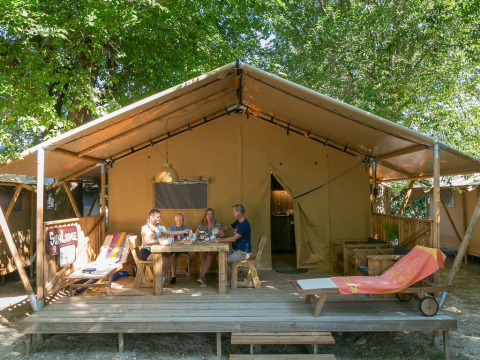 Cuatro personas disfrutan de una comida frente a una tienda SunLodge Bintulu en Camping Village Poljana, Croacia.