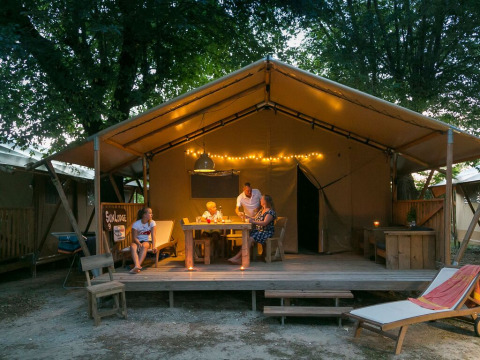 Familia disfrutando en SunLodge Bintulu del Camping Village Poljana en Croacia, rodeados de luces cálidas.