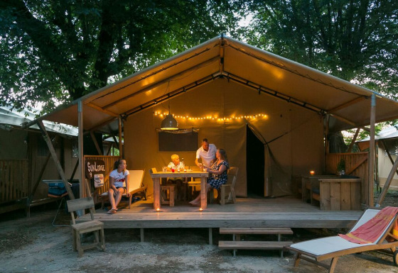 Familia disfrutando en SunLodge Bintulu del Camping Village Poljana en Croacia, rodeados de luces cálidas.