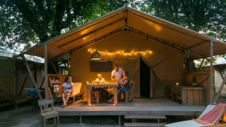 Familia disfrutando en SunLodge Bintulu del Camping Village Poljana en Croacia, rodeados de luces cálidas.