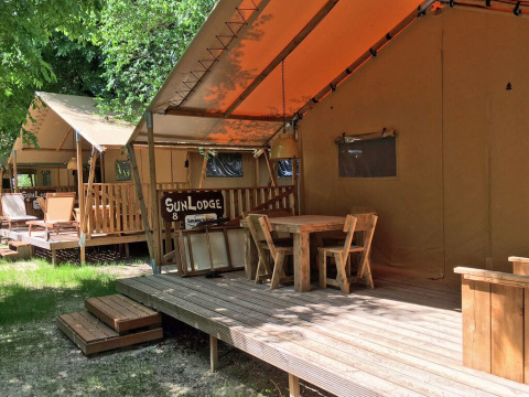 Terraza de madera con mesa y sillas frente a carpas SunLodge en Camping Village Poljana en Croacia.