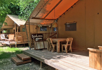 Veranda in legno con tavolo e sedie davanti alle tende SunLodge al Camping Village Poljana in Croazia.