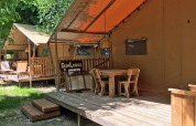 Terraza de madera con mesa y sillas frente a carpas SunLodge en Camping Village Poljana en Croacia.