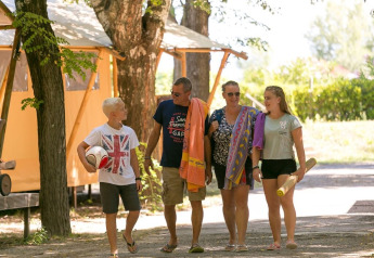 Familie går sammen ved SunLodge Bintulu på Camping Village Poljana i Kroatien, omgivet af træer og telte.