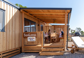 Gezin op het houten terras bij SunLodge Catalpa op Camping Village Poljana, Kroatië, met zonnig weer.