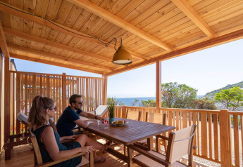 Koppel op houten terras van SunLodge Catalpa, Camping Village Poljana, Kroatië, met uitzicht op zee.