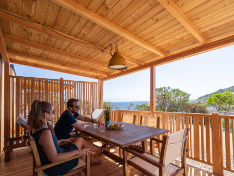 Pareja relajándose en la terraza de madera de SunLodge Catalpa, Camping Village Poljana, Croacia.