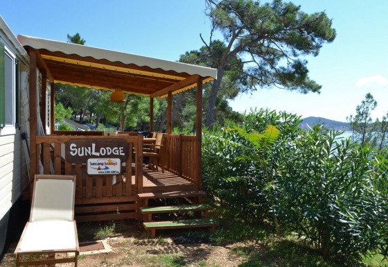 Solbeskinnet terrasse og stol ved SunLodge Redwood på Camping Village Poljana i Kroatien med udsigt til havet.