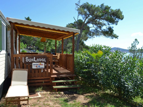 Terraza soleada y tumbona en SunLodge Redwood del Camping Village Poljana en Croacia, con vistas al mar.