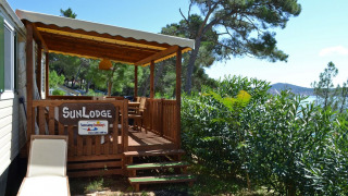 Terraza soleada y tumbona en SunLodge Redwood del Camping Village Poljana en Croacia, con vistas al mar.