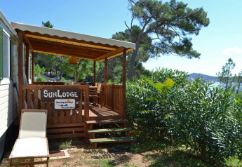 Zonnig terras en ligstoel aan SunLodge Redwood op Camping Village Poljana in Kroatië met zeezicht.