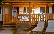 Vista nocturna de SunLodge Redwood en Camping Village Poljana, Croacia, con porche y tumbonas iluminados.