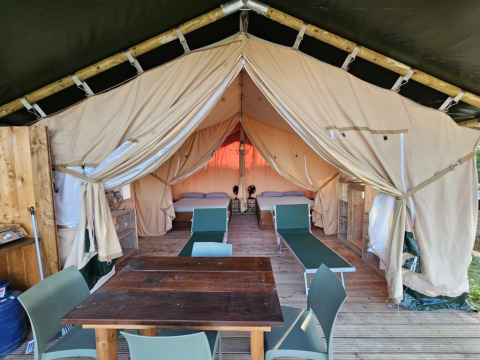 Vista interna di una tenda safari presso Agricola La Casetta in Italia, con letti e zona pranzo.