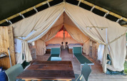 Interior view of a safari tent lodge at Agricola La Casetta in Italy, featuring beds and dining area.