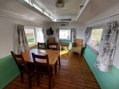 Comedor con mesa y sillas de madera en Pipowagen Snuf en Camping De Gouwe Stek, Países Bajos.